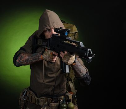 the man Stalker with a gun with an optical sight and a backpack on a dark background with emotions looking, aiming, watching, sneaking