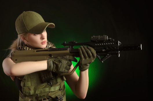 girl in military special clothes posing with a gun in his hands on a dark background in the haze