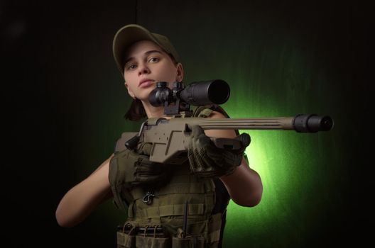 girl in military special clothes posing with a gun in his hands on a dark background in the haze