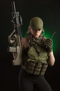 girl in military special clothes posing with a gun in his hands on a dark background in the haze