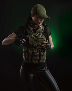 girl in military special clothes posing with a gun in his hands on a dark background in the haze