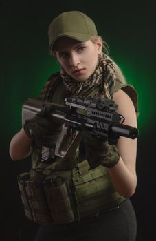 girl in military special clothes posing with a gun in his hands on a dark background in the haze