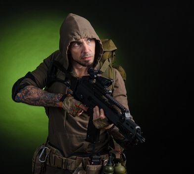 the man Stalker with a gun with an optical sight and a backpack on a dark background with emotions looking, aiming, watching, sneaking