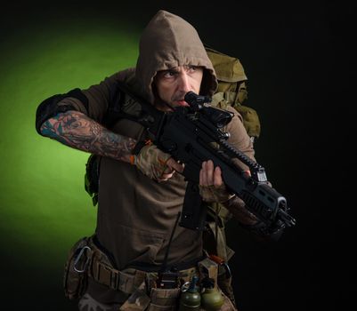 the man Stalker with a gun with an optical sight and a backpack on a dark background with emotions looking, aiming, watching, sneaking