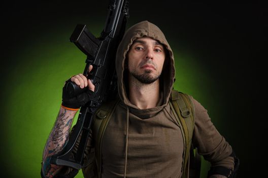 the man Stalker with a gun with an optical sight and a backpack on a dark background with emotions looking, aiming, watching, sneaking