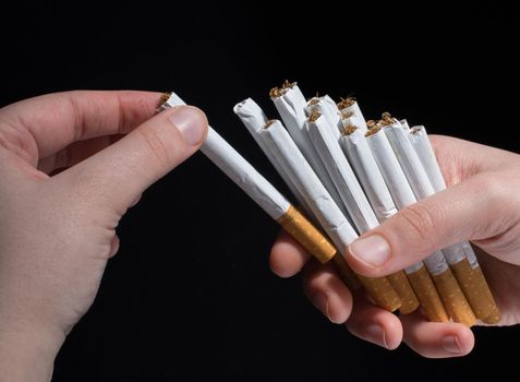 Hand is giving out bundle of cigarettes on black background