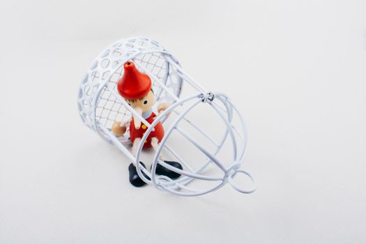 Metal cage and Little puppet pinocchio made of wood