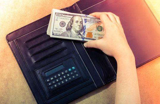 Hand holding American dollar  banknotes isolated on wooden background