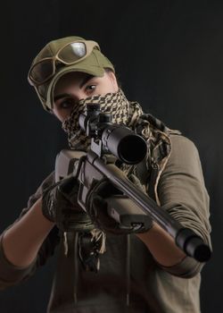 girl in military special clothes posing with a gun in his hands on a dark background in the haze