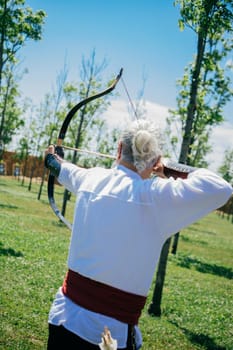 Archer with bow  in traditional clothes shooting an arrow