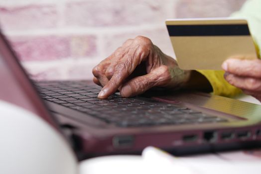 senior women holding credit card and using laptop shopping online ,