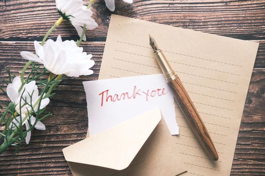 thank you message and envelope on wooden table.