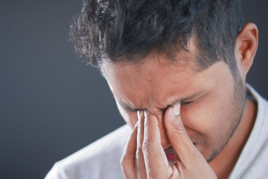 Close up of upset man suffering from strong eye pain.