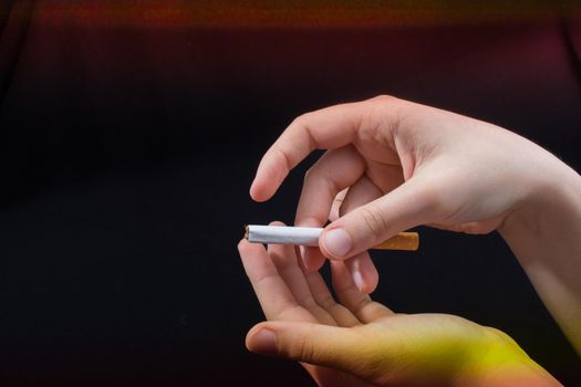 Hand is holding a cigarette on black background