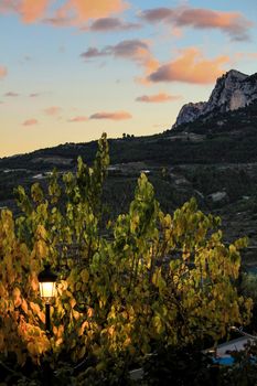 Sunset in Guadalest village with beautiful view of the valley. Vintage lamppost in the foreground.