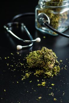 the Dry medical cannabis in a jar with a stethoscope on a black background