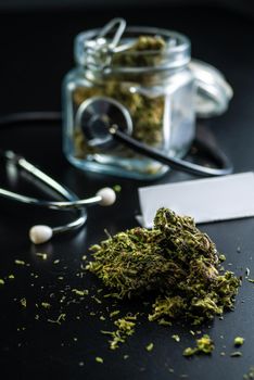 the Dry medical cannabis in a jar with a stethoscope on a black background