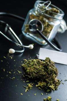 the Dry medical cannabis in a jar with a stethoscope on a black background