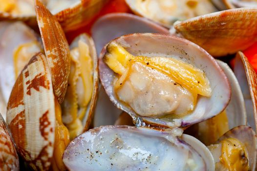 fresh clams stewed on an iron skillet over wite rustic wood table 