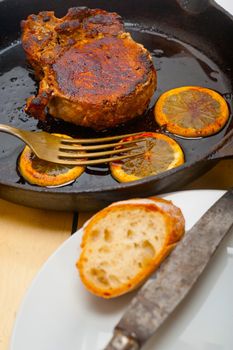 pork chop seared on iron skillet with lemon and spices seasoning