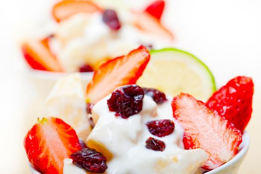 fruit and yogurt salad healthy breakfast over white wood table