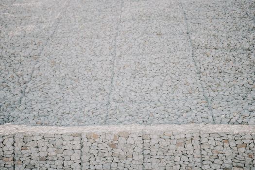 strengthening the slope with stones behind the wire. grey texture. construction. Granite stones behind a metal grate