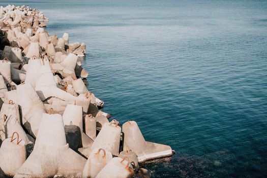 The seashore is reinforced with concrete tetrapods. Protection of the shore from blurring. Sea waves. Concrete tetrapod breakwaters lie all along the coast.