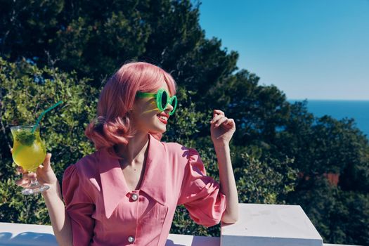 Delighted young girl in green sunglasses with cocktail in summer outdoors unaltered. High quality photo