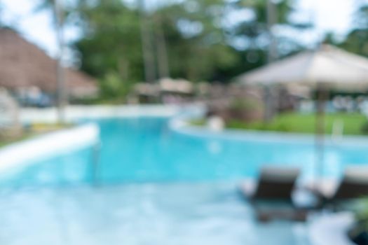 Background of a blurry resort and hotel with a swimming pool and a beach chair.