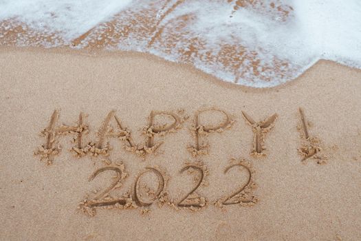 Happy 2022 word on the sand at the beach to show life ahead next year copyspace background