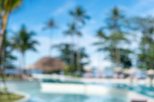 Background of a blurry resort and hotel with a swimming pool and a beach chair.