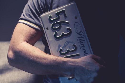 Caucasian Male Holding License Plate From Car In Illinois.