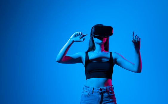 Young woman using the virtual reality headset and interact with a virtual world in a metaverse. Female model wearing VR goggles