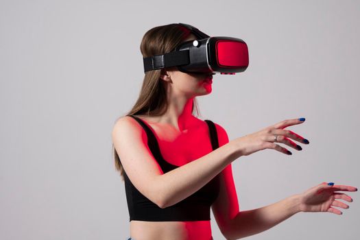 Woman using virtual reality glasses in a studio. Business woman wearing VR goggles and interacts with cyberspace using swipe and stretching gestures