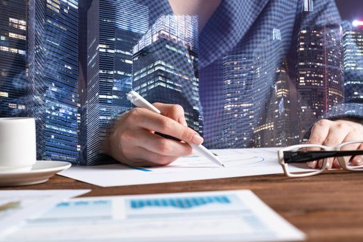 Corporate consultant analyze financial analytics. Double exposure concept with woman hands and modern skyscrapers. Analyst in suit working at workplace in office. Real estate investment company.