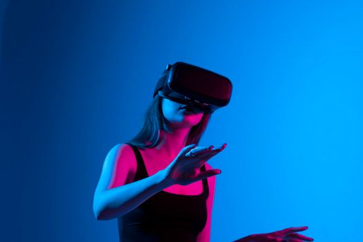Woman enjoying a VR experience. Woman with VR headset touching invisible screen. Future technology concept