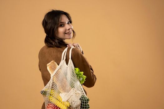 Zero waste concept. Young woman holding reusable cotton shopping mesh bag with groceries from a market. Concept of no plastic. Zero waste, plastic free. Eco friendly concept. Sustainable lifestyle
