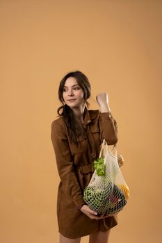 Reusable eco bag for shopping. String shopping bag with fruits and vegetables in the hands of a young woman. Zero waste, plastic free concept. Eco lifestyle. Eco shopping
