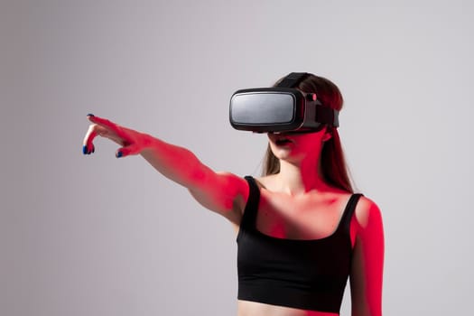 Young handsome woman wearing virtual headset and playing a game in red light. Excited hipster using VR glasses