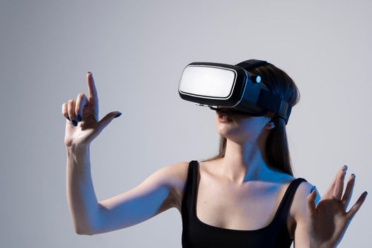Happy young woman playing on VR glasses. Virtual reality concept with young girl having fun in virtual reality goggles. Metaverse