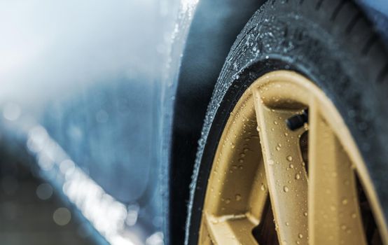 Weather Elements and the Car Wheels. Water on Elegant Golden Alloy Wheels. Transportation and Automotive Industry Theme.