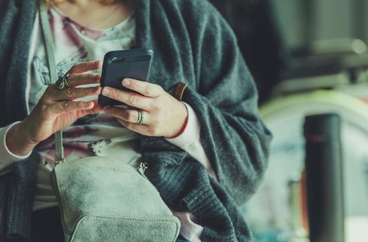 Caucasian Woman in Her 40s with Smartphone in an Airport Waiting Room. Browsing Internet Using Free WiFi Network.