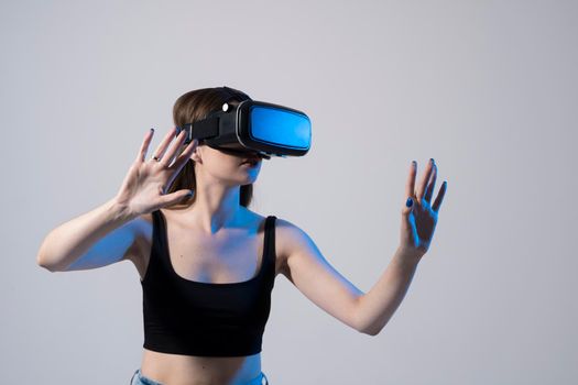 Portrait of young woman playing in VR-glasses in neon light on blue background. Concept modern gadgets and technologies. Future technology concept. Virtual reality gaming