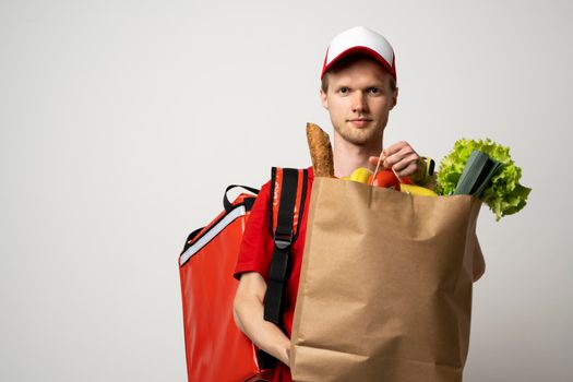 Delivery of food packages. Man with a thermal bag holding a paper bag of groceries on a white background