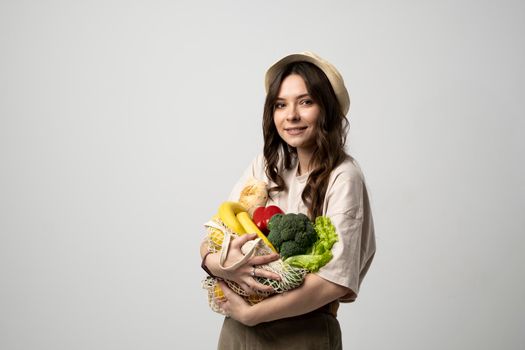 Zero waste concept with copy space. Woman holding a reusable mesh shopping bag with vegetables, products. Eco friendly mesh shopper. Zero waste, plastic free concept