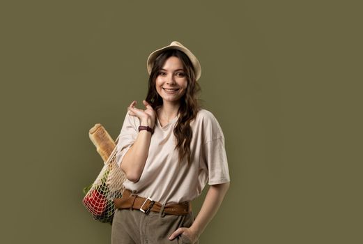 Young woman holding mesh grocery bag with vegetables Concept of no plastic. Zero waste, plastic free. Eco friendly concept. Sustainable lifestyle