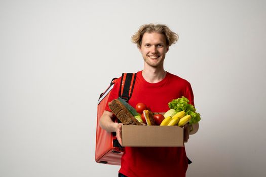 Handsome delivery man carrying package box of grocery food and drink from store. Isolated on white studio Background. Copy Space. Delivery Concept