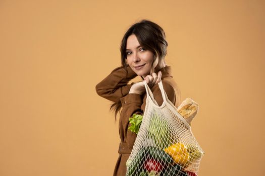 Zero waste concept. A young brunete girl holds on her shoulder a textile eco bag with groceries. Plastic free concept. Eco lifestyle. Eco shopping. Conscious consumption. Eco trend