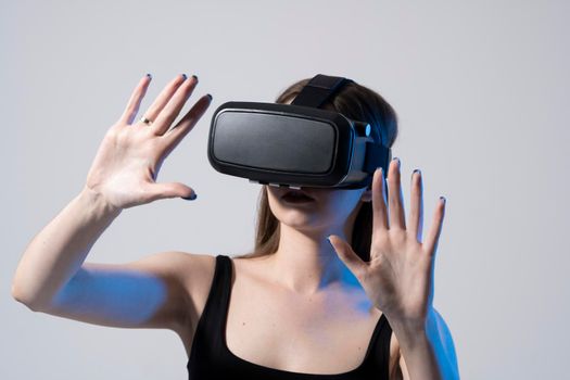 Modern architect, designer woman wearing VR goggles and interacts with metaverse using swipe and stretching gestures. Future technology concept