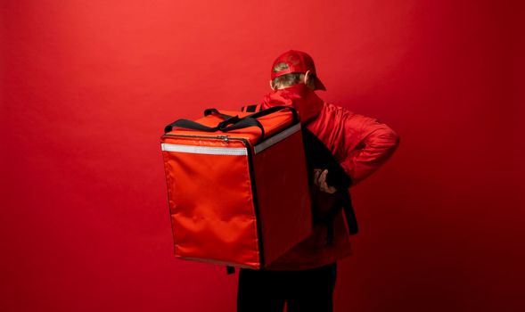 Delivery man in red uniform with a thermal backpack isolated on a white background. Fast home delivery. Online order. Courier delivers groceries home